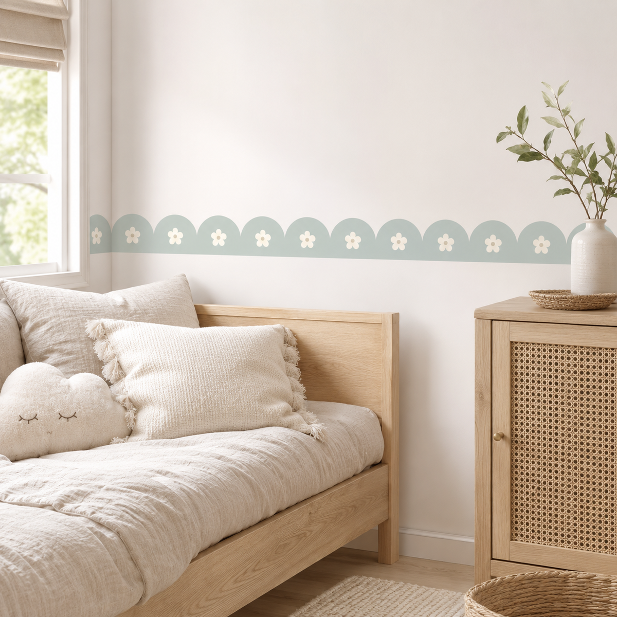 Misty Aqua daisy scalloped peel-and-stick wallpaper border behind a wooden daybed with cream cushions beside a cane-front cabinet.