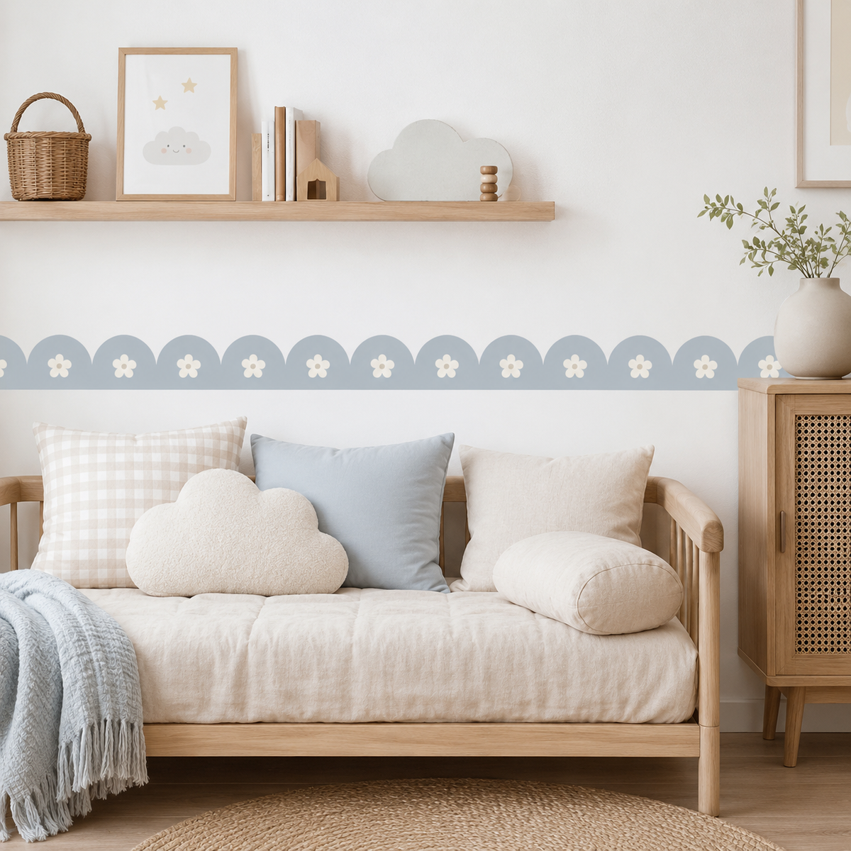 Powder Blue daisy scalloped peel-and-stick wallpaper border behind a cream sofa with blue and neutral cushions.