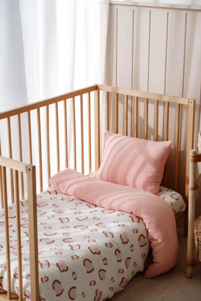 A beautiful display of baby and toddler bedding sets featuring premium muslin and cotton sateen fabrics in a wooden crib